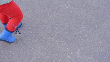 Closeup-high-angle-view-of-toddler-with-vibrant-blue-shoes-and-red-pants-walk