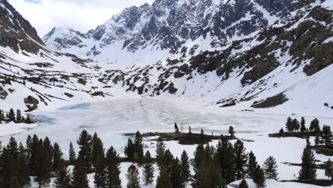snow-capped mountain landscape with a frozen lake and pine trees