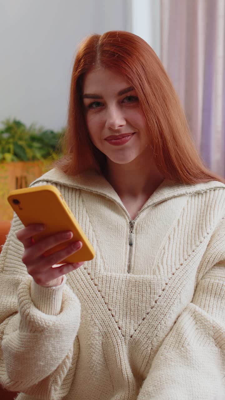 Giovane donna che utilizza una carta di credito e uno smartphone per trasferire denaro e fare acquisti online