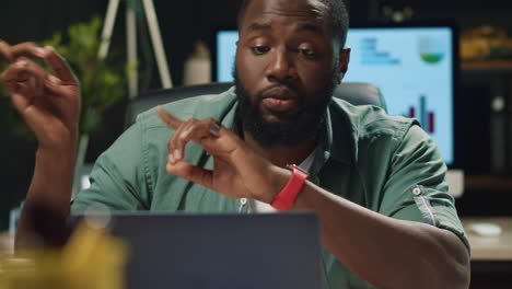 Portrait-of-african-american-business-man-speaking-by-laptop-in-night-office