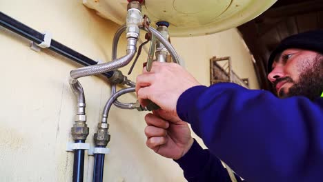 Plano-Medio-De-Un-Fontanero-Observando-Y-Arreglando-Un-Calentador-De-Agua-Eléctrico