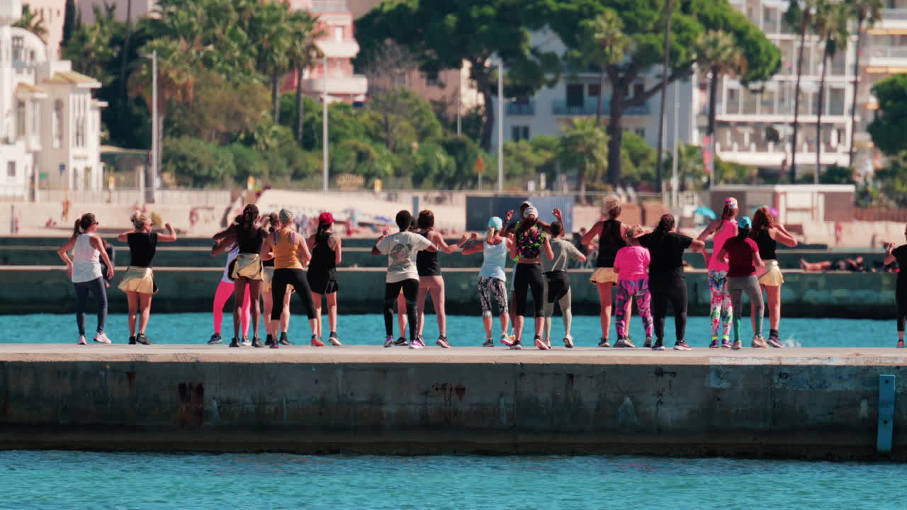 Cannes, France - October 7, 2025: A group of people practicing dance or fitness on a pier by the sea on a sunny day