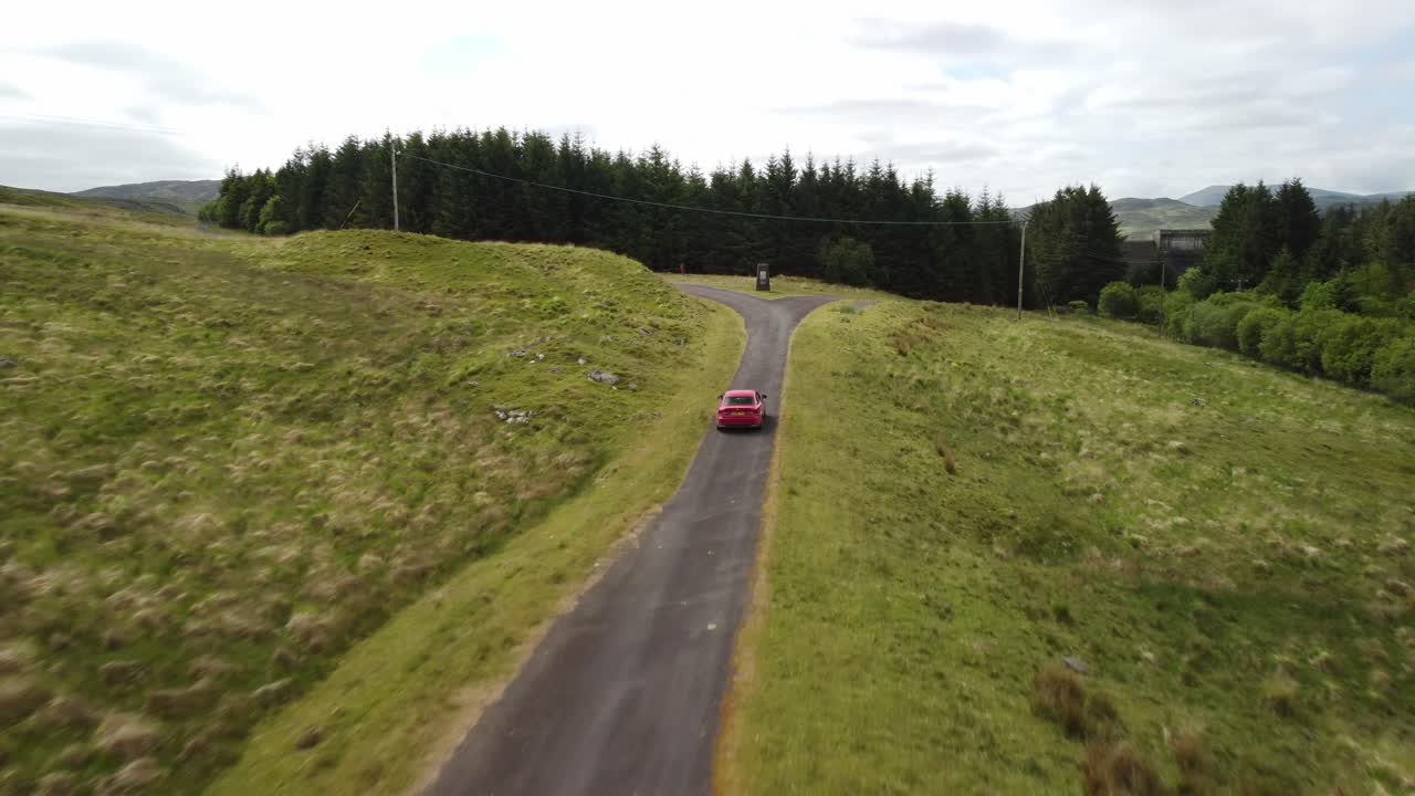 단일 트랙 시골 도로를 따라 뒤쪽에서 드론으로 추적되는 빨간 차량