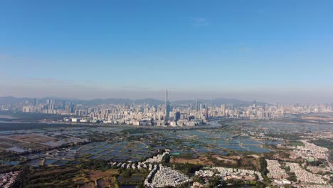 hong kong and shenzhen border line over hong kong rural houses with shenhzen skyline in the horizon, aerial view