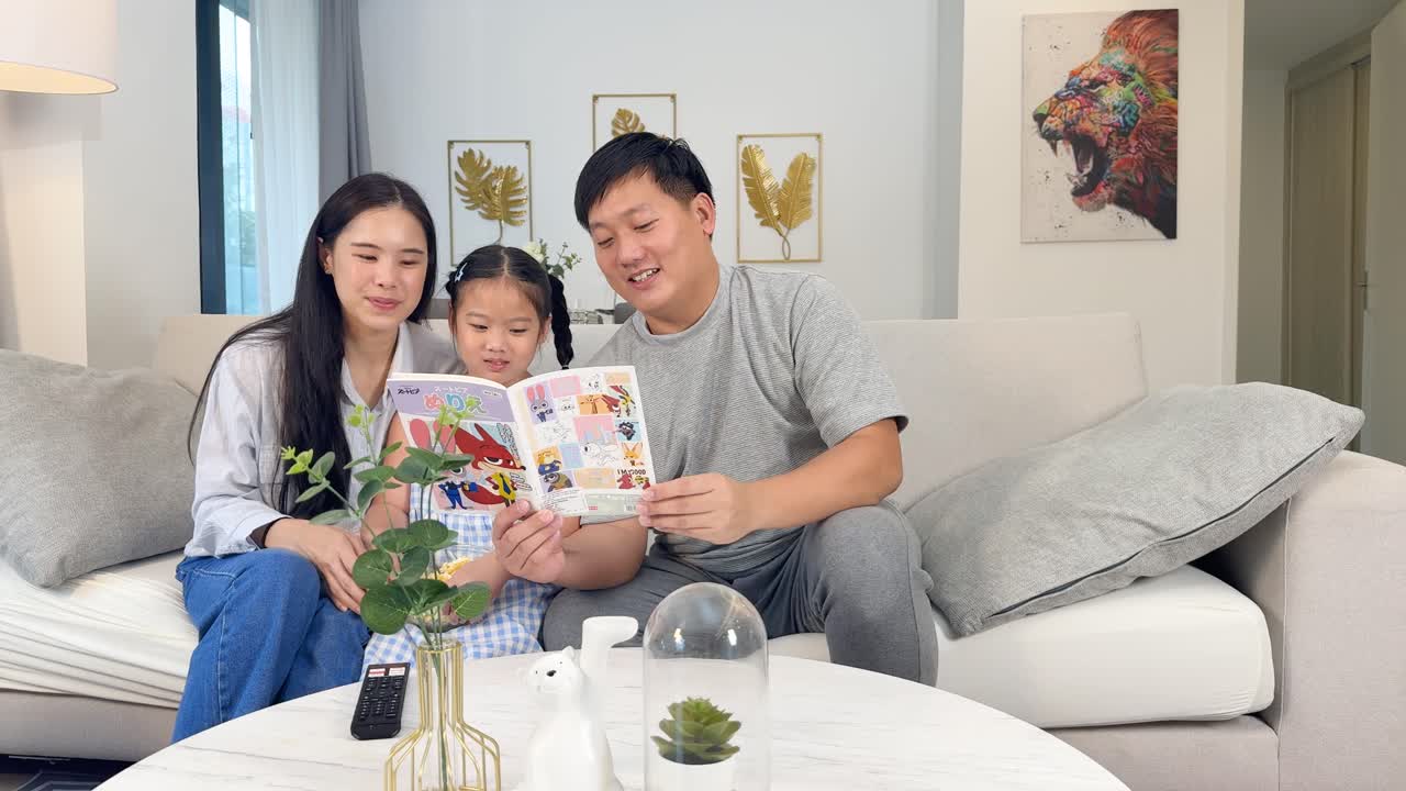 居心地の良いリビングのソファで、幼い娘と一緒に本を読む幸せそうな家族