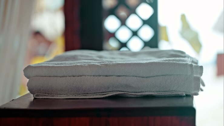 Woman putting fresh towels on the table and flower on it