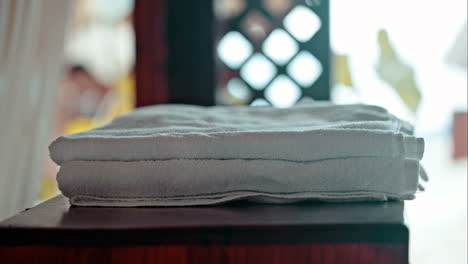 Woman-putting-fresh-towels-on-the-table-and-flower-on-it