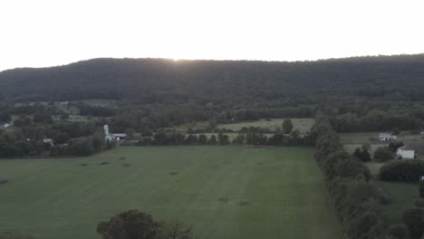 drone shot coming up from the trees and looking into the mountain with the sun setting directly behind it in 4k 24p d-log