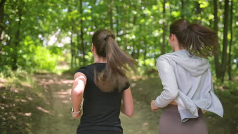 Back-View-Of-Two-Happy-Sportswomen-Running-In-The-Woods