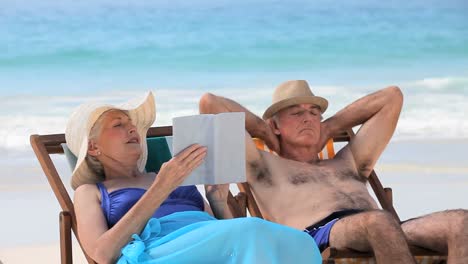 elderly couple relaxing on beach chairs