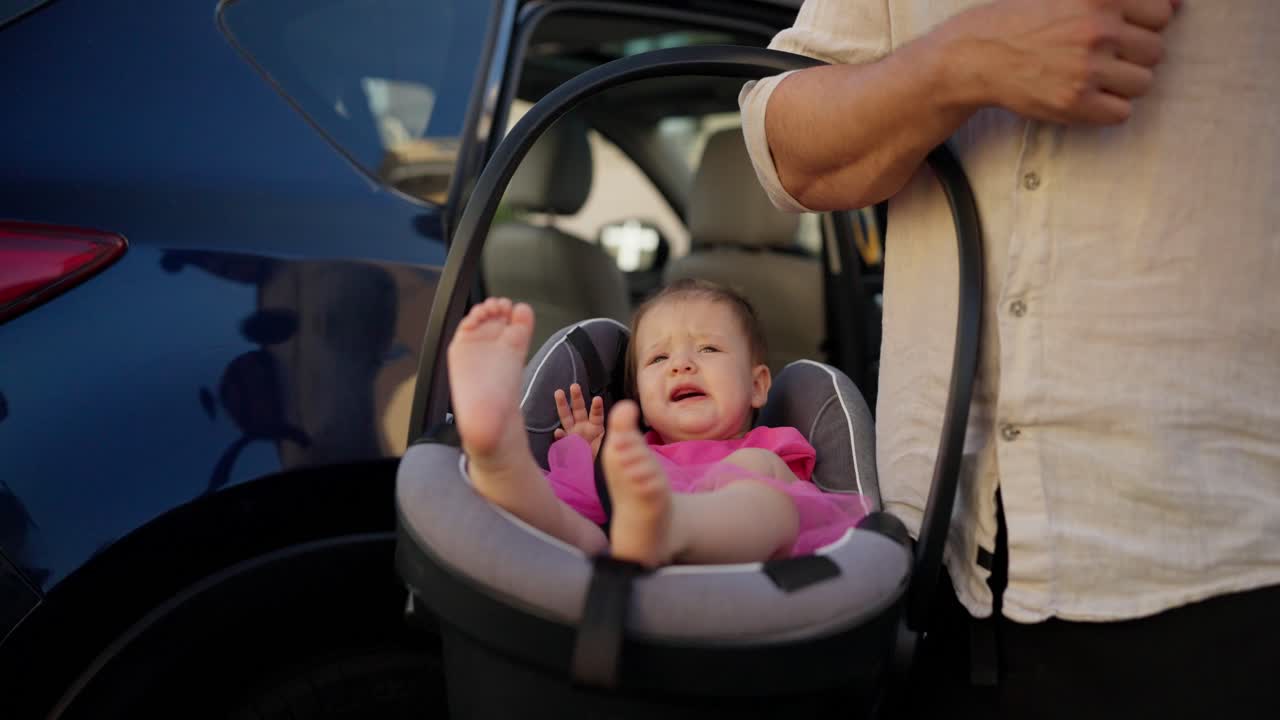부모 가 들고 있는 동안 차 의자 에서 울고 있는 아기