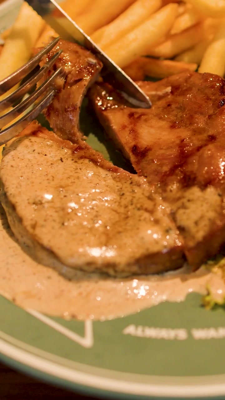 Nærbilde av å skjære en saftig grillet svinesteik servert med kremet peppersaus