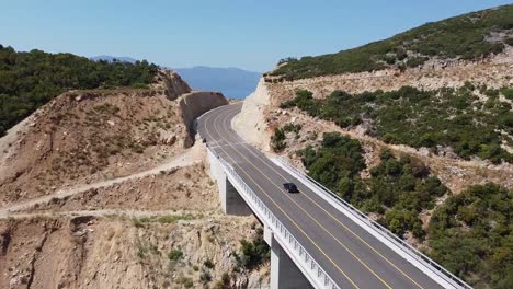 Aerial-view-of-black-car-crossing-a-bridge-on-the-highway