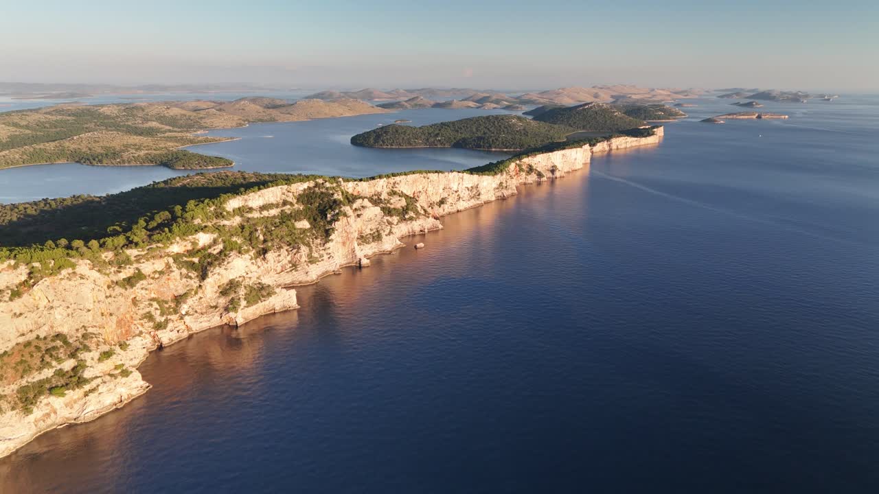 Drone glides along Telascica cliffs on Dugi Otok, revealing Kornati islands in golden sunset light over the Adriatic