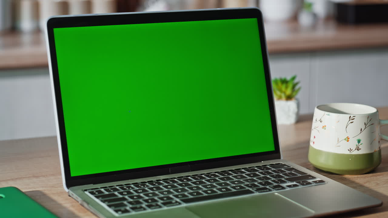 Unrecognizable woman typing greenscreen laptop computer at light kitchen closeup
