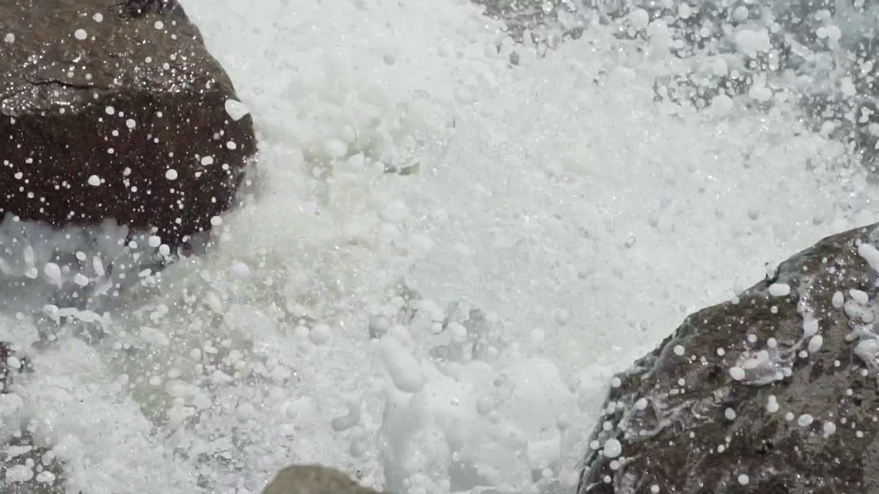Looking down on a crab as waves crash against the rocky coastline of Playa Salverry beach, Trujillo, La Libertad, Peru, SLOW MOTION