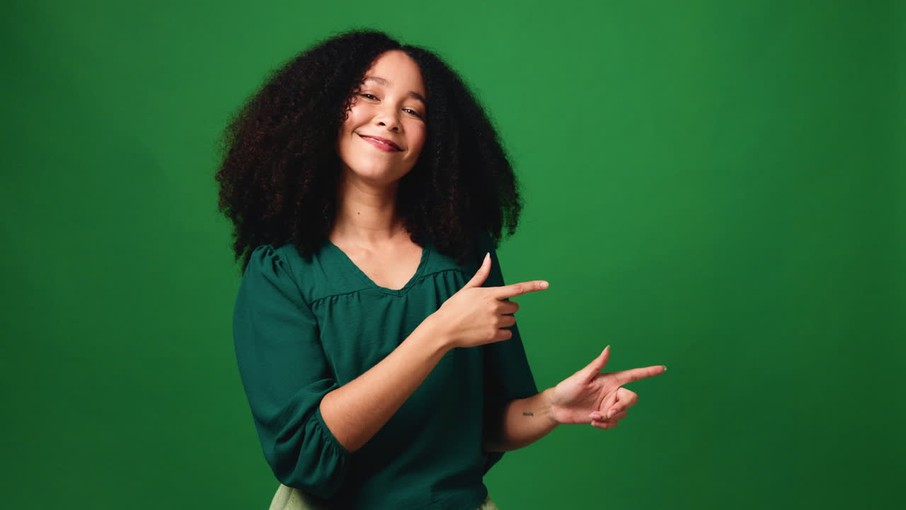 A smiling woman pointing on a green screen