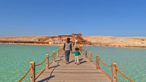 father and son walking on wooden pear in exotic tropical location, back view