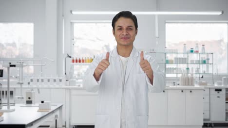 행복한 인도 과학자가 엄지손가락을 올리고 있습니다.