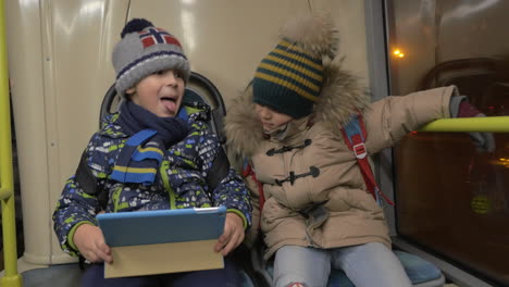 two young boys riding on a commuter bus