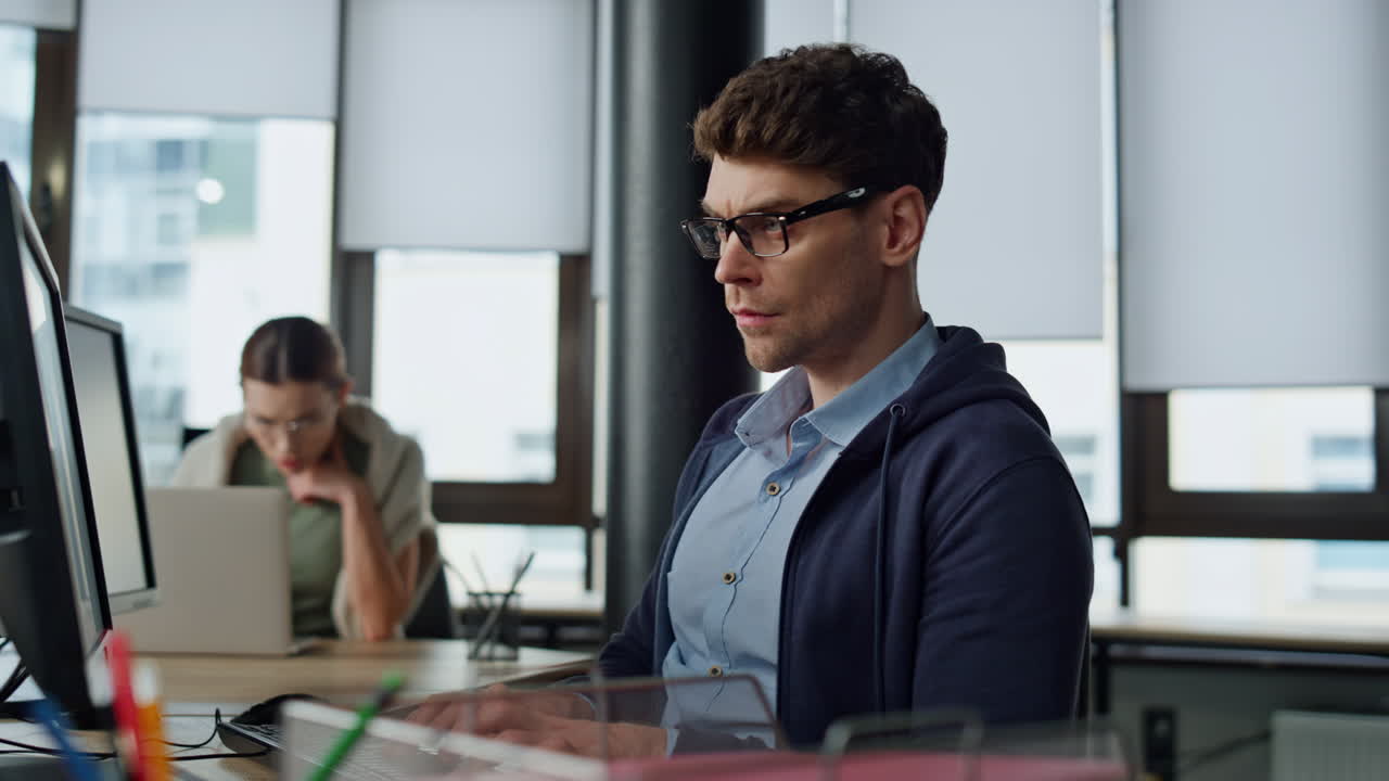 Serious it guy typing computer in office. Professional programmer code using two