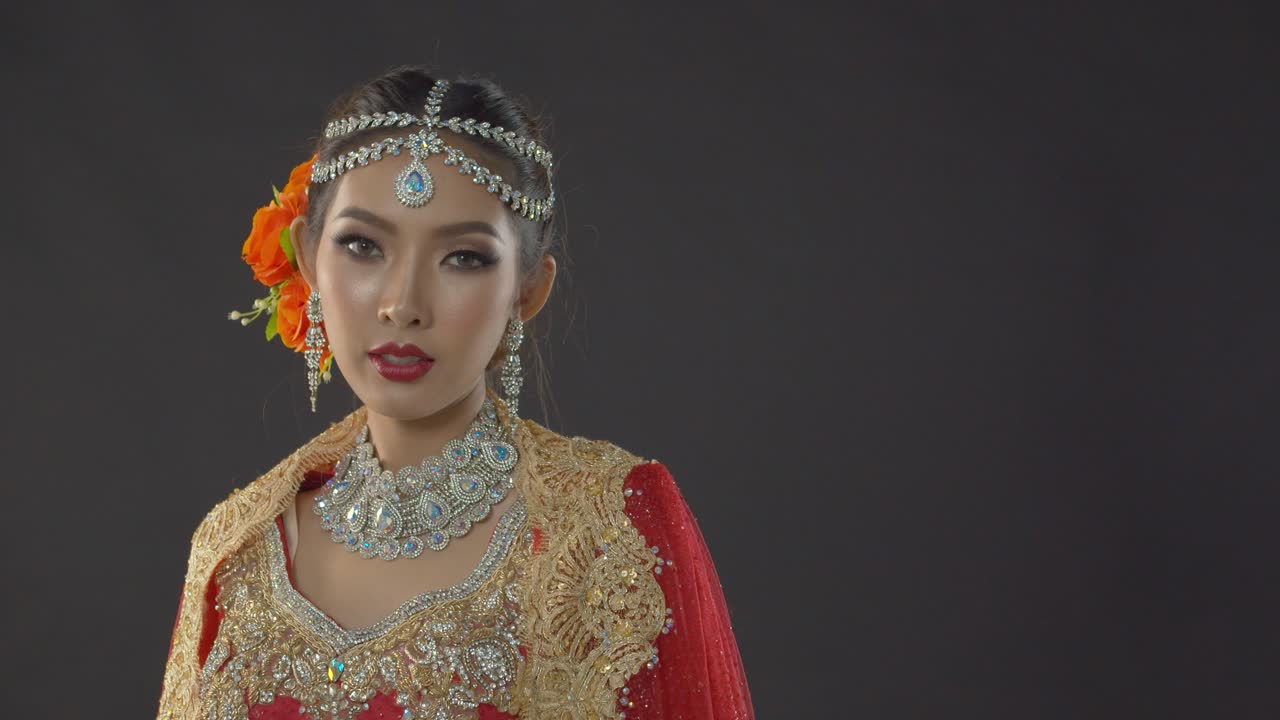 Mysteriously attractive Indian bride posing while dressed in traditional dress on her wedding day