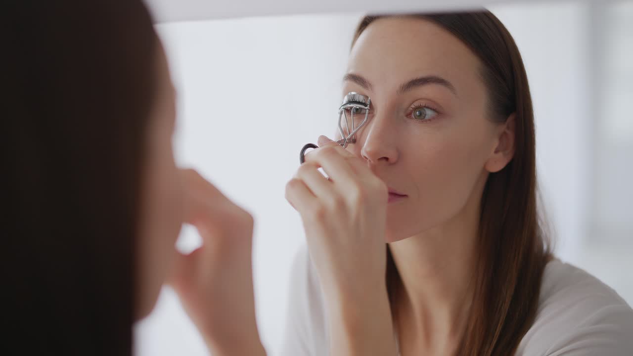 mujer aplicando rizador de pestañas