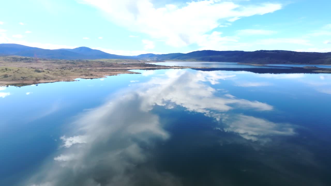 Aerial: Drone shot of large white cloud reflected in the water of Lake Jindabyne, NSW Australia