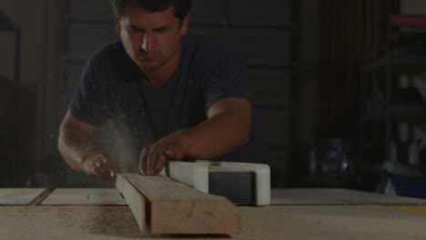 A-woodworker-saws-a-plank-on-a-workbench-2