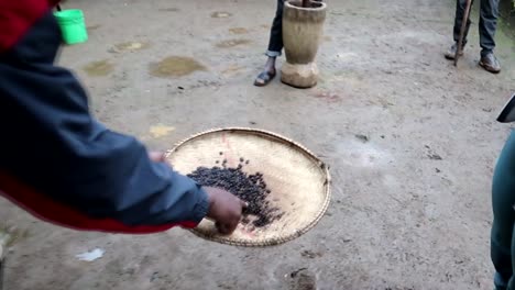 cerca de la gente de la tribu chagga africana vertiendo granos de café tostados calientes en el tamiz para tamizarlos