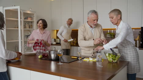 Group-Of-Older-Friends-Cooking-In-The-Kitchen-While-Talking-And-Laughing