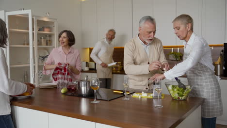 grupo de amigos mais velhos cozinhando na cozinha enquanto conversam e riem