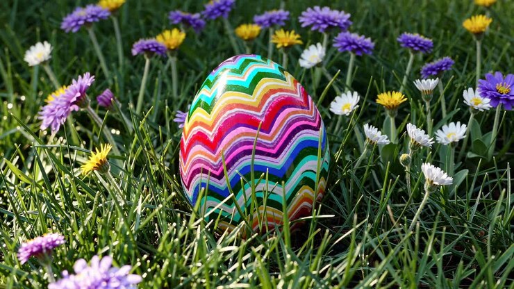 Colorful Easter egg with zigzag patterns nestled in grass and wildflowers