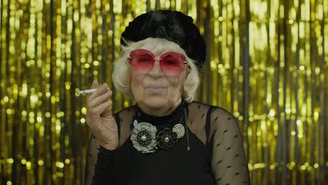 elderly style mature businesswoman in fashion black clothes in sunglasses posing, smoke cigarette