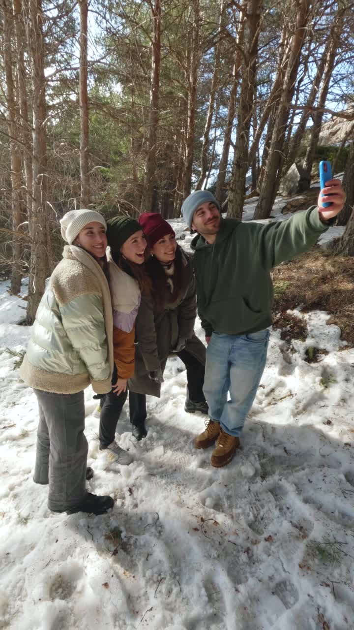 Group of friends taking a selfie in a snowy forest during winter