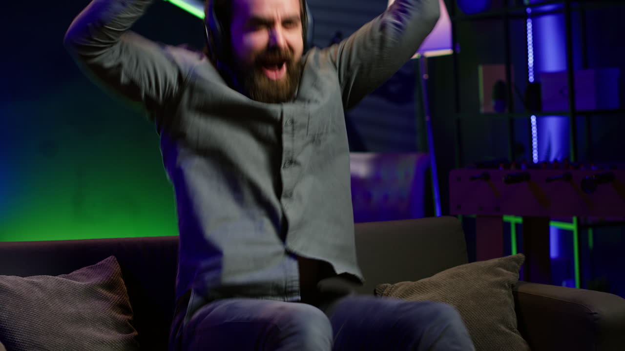 hombre extático jugando en casa gritando de alegría después de lograr la victoria