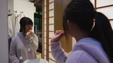 Asian-girl-standing-in-bathroom-and-brushing-teeth