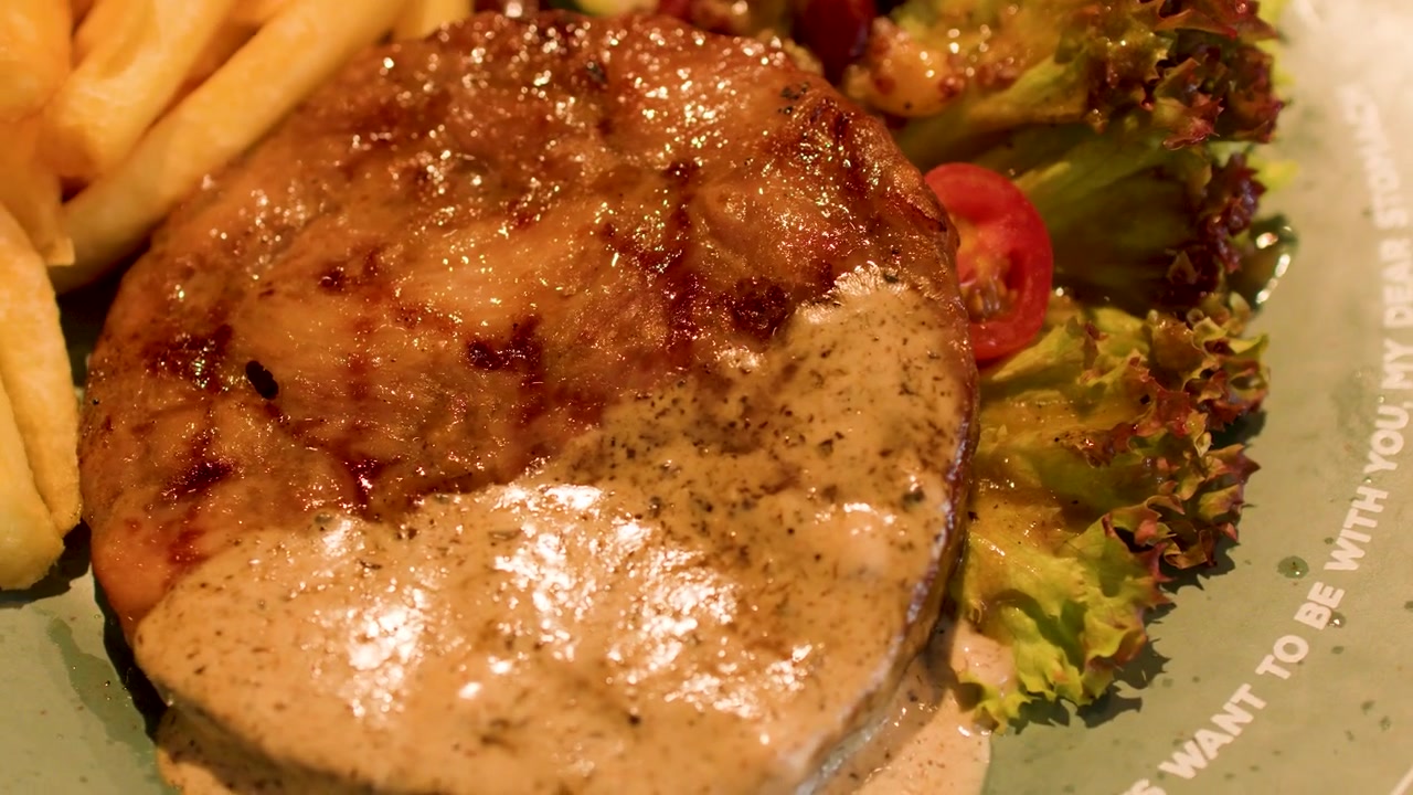 Primo piano di una bistecca alla griglia con salsa cremosa ai funghi, patatine fritte dorate e insalata