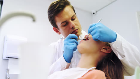 dentista examinando a una paciente femenina con herramientas