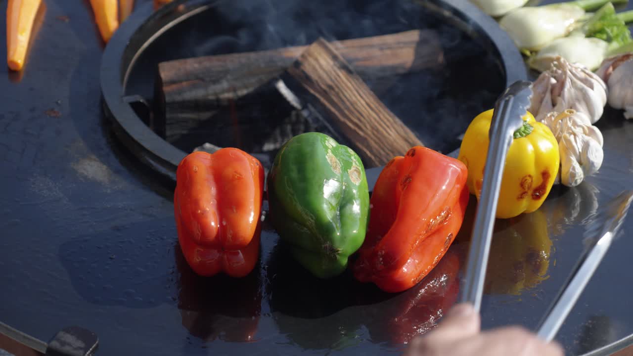 chef using metal tongs to cook the vegetables evenly on all sides on a bbq