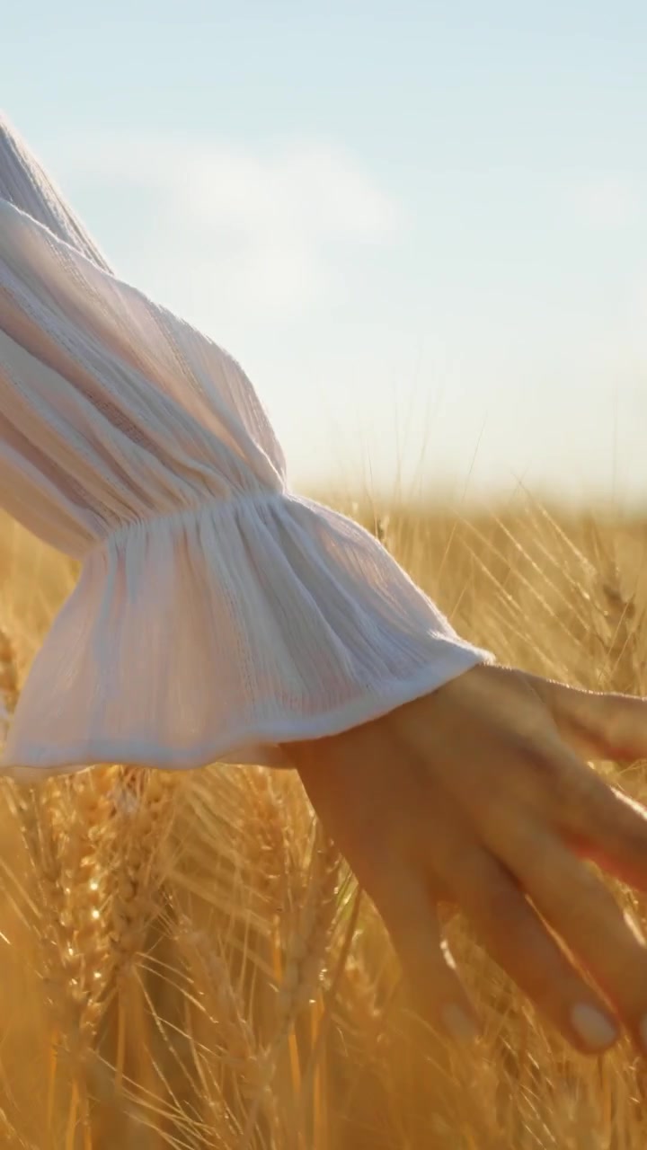 Donna in abito bianco che cammina in un campo di grano dorato