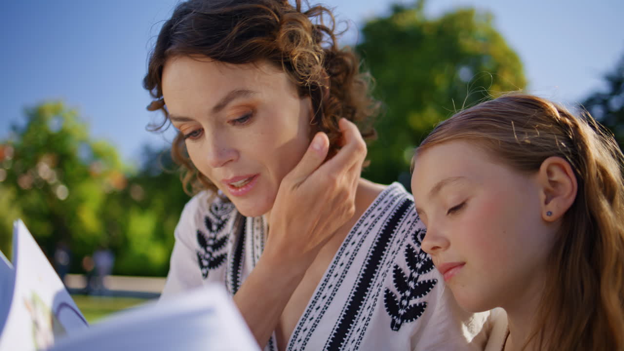 Mom child holding book gathering in cozy garden closeup. Lady and kid talking