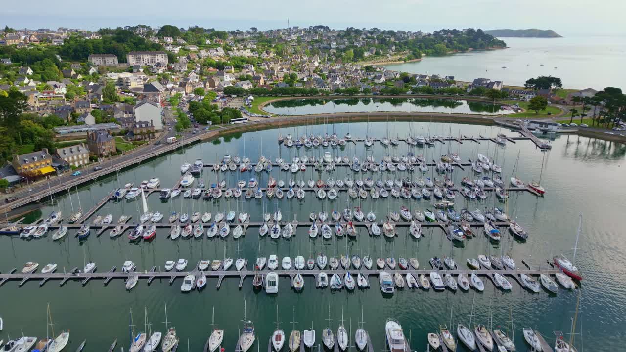 Drone flying over Perros-Guirec harbor with sailboats, coastal town, bridge, Brittany, France. Aerial drone forward