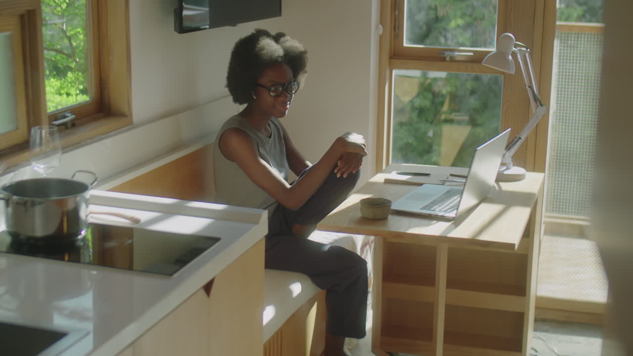 Black Woman Chatting via Video Call on Laptop at Home