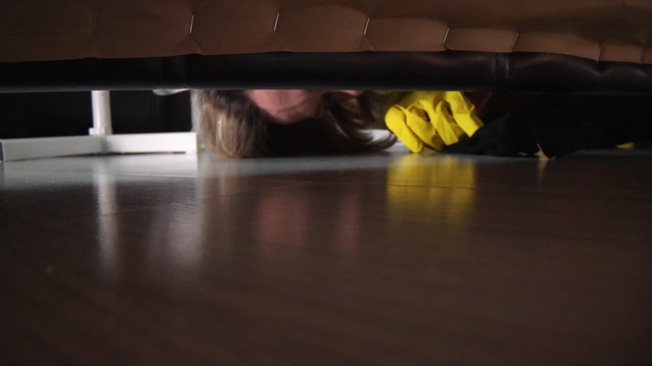 Person cleaning under furniture