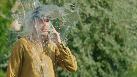 man gets water poured on him while talking on phone