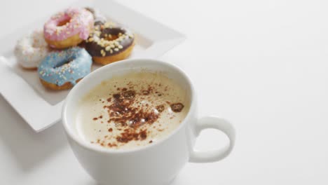 Video-Von-Donuts-Mit-Zuckerguss-Und-Einer-Tasse-Kaffee-Auf-Weißem-Teller-Vor-Weißem-Hintergrund