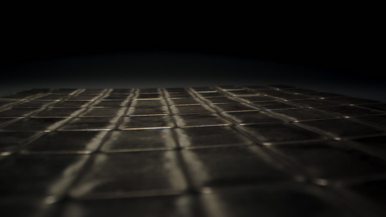 Cinematic dolly out of loads of silver bars in a dark vault. The precious metal plates are neatly organized while the camera moves over them