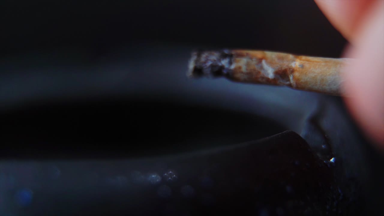 un primer plano macro de residuos de ceniza de un cigarrillo en un cenicero de piedra negra, video de 4k en cámara lenta, humo blanco 5