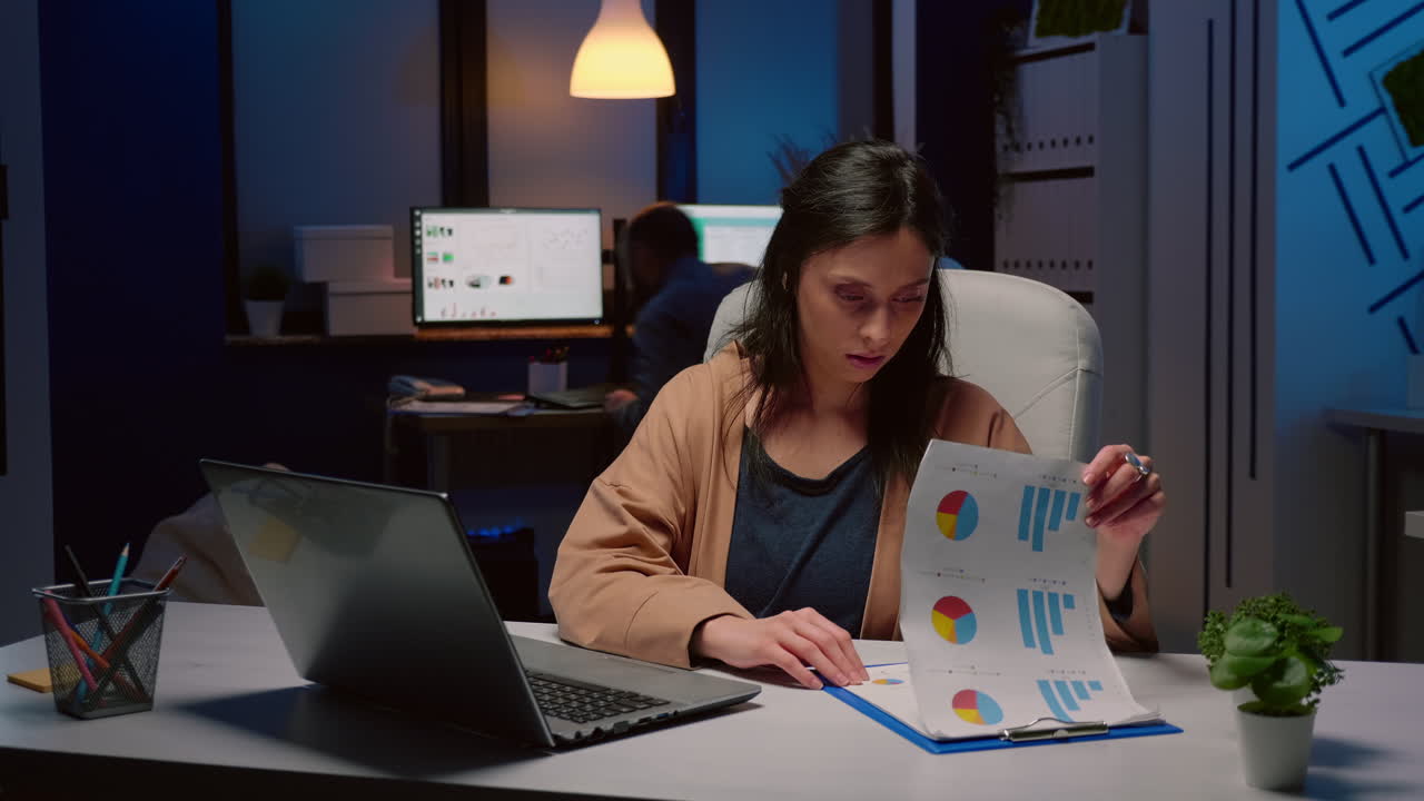 Empresaria adicta al trabajo agotada revisando estrategia de marketing en oficina de startup